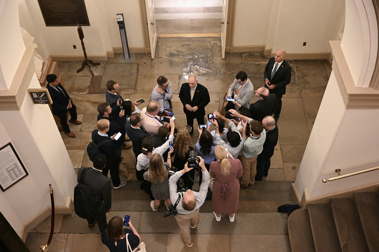 A representative in a hallway of the House of Representatives attending to reporters.